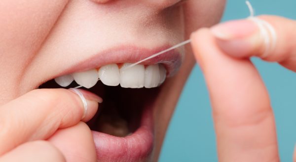 Oral hygiene and health care. Smiling women use dental floss white healthy teeth.